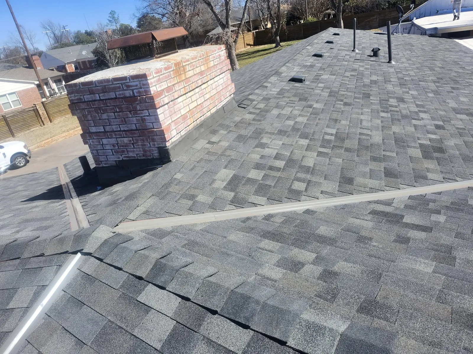 Completed shingle roof around a brick chimney