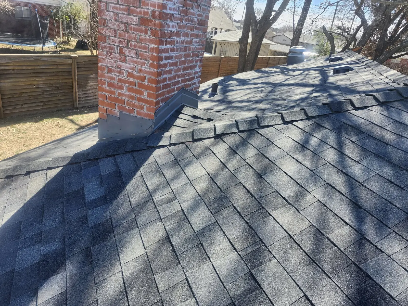 Completed shingle roof showing a roof valley and chimney